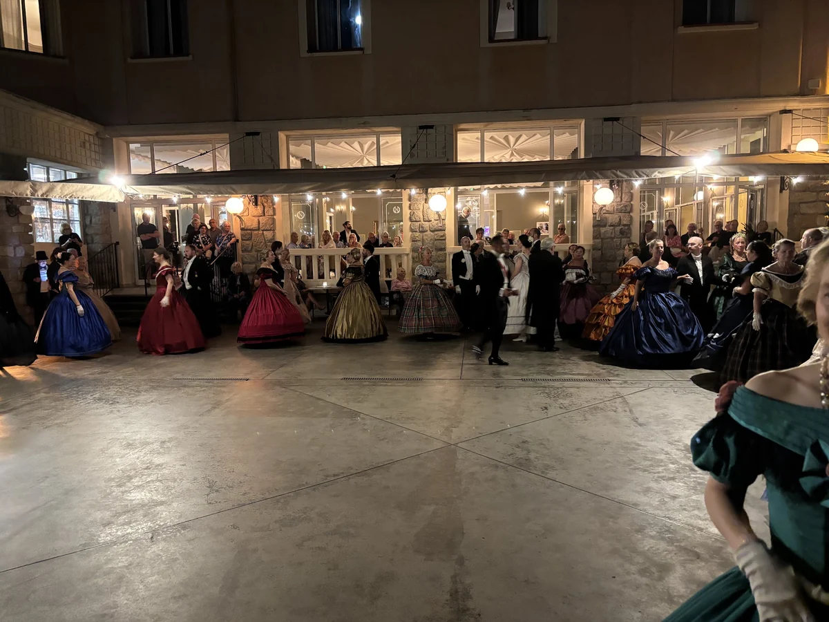Danseurs en robes de bal et habits disposés autour de la piste éclairée